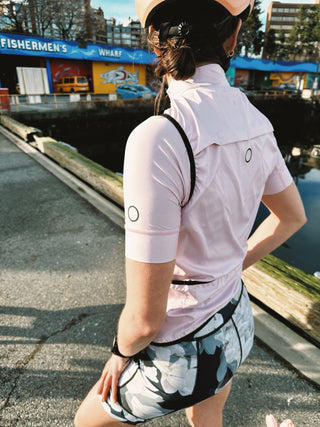 Woman outdoors wearing Samara Magnolia cycle shorts and Cherry Blossom jersey and vest.